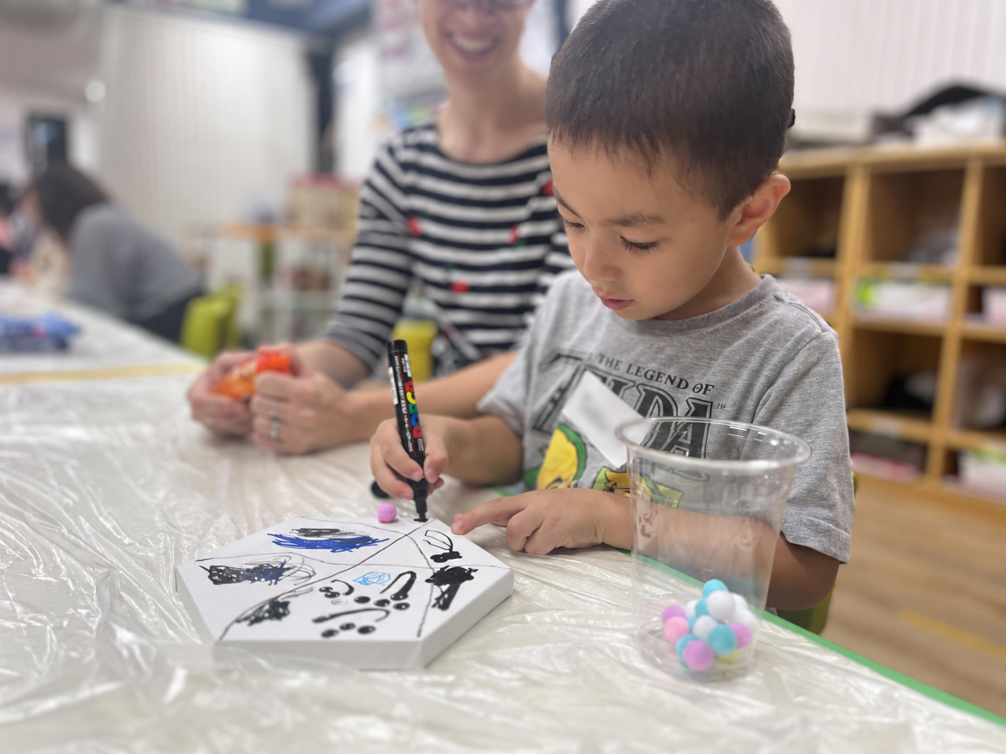 保護者が見守る中、ペンで作品づくりに取り組む子ども
