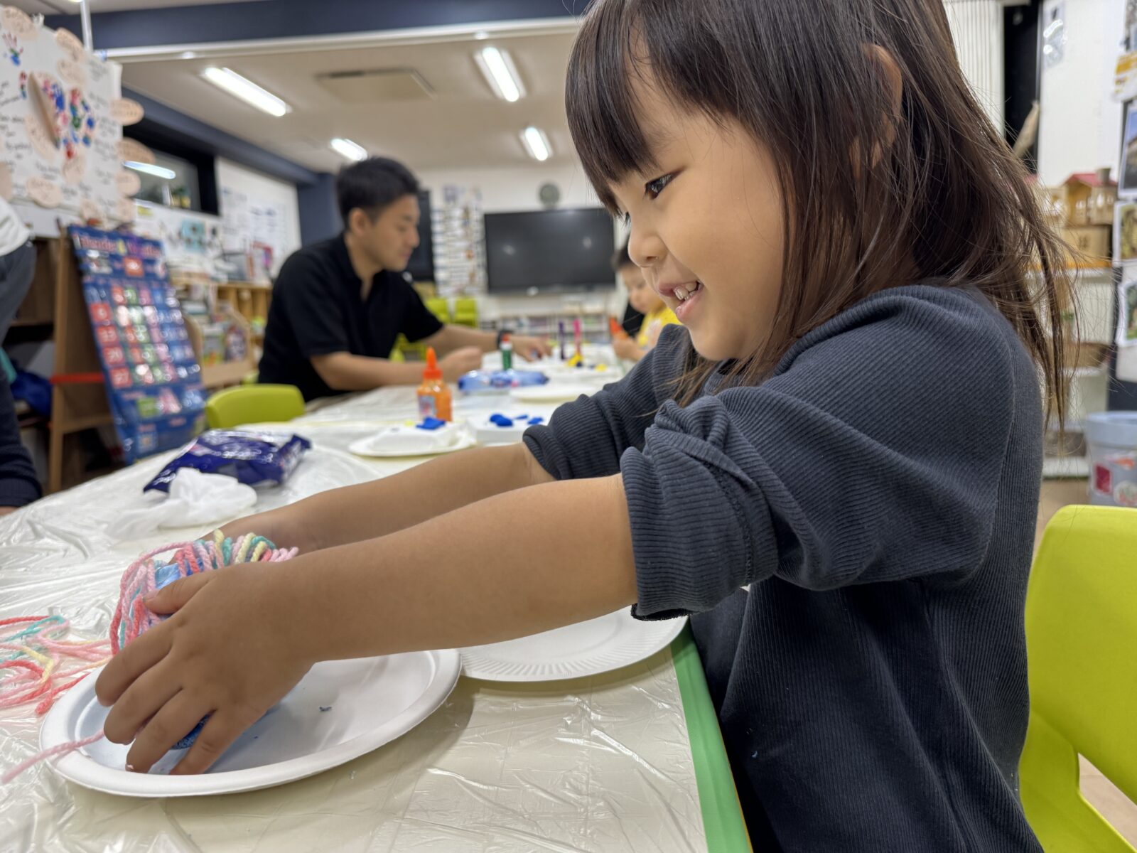 毛糸などの材料に手を伸ばしながら作品をつくる子ども