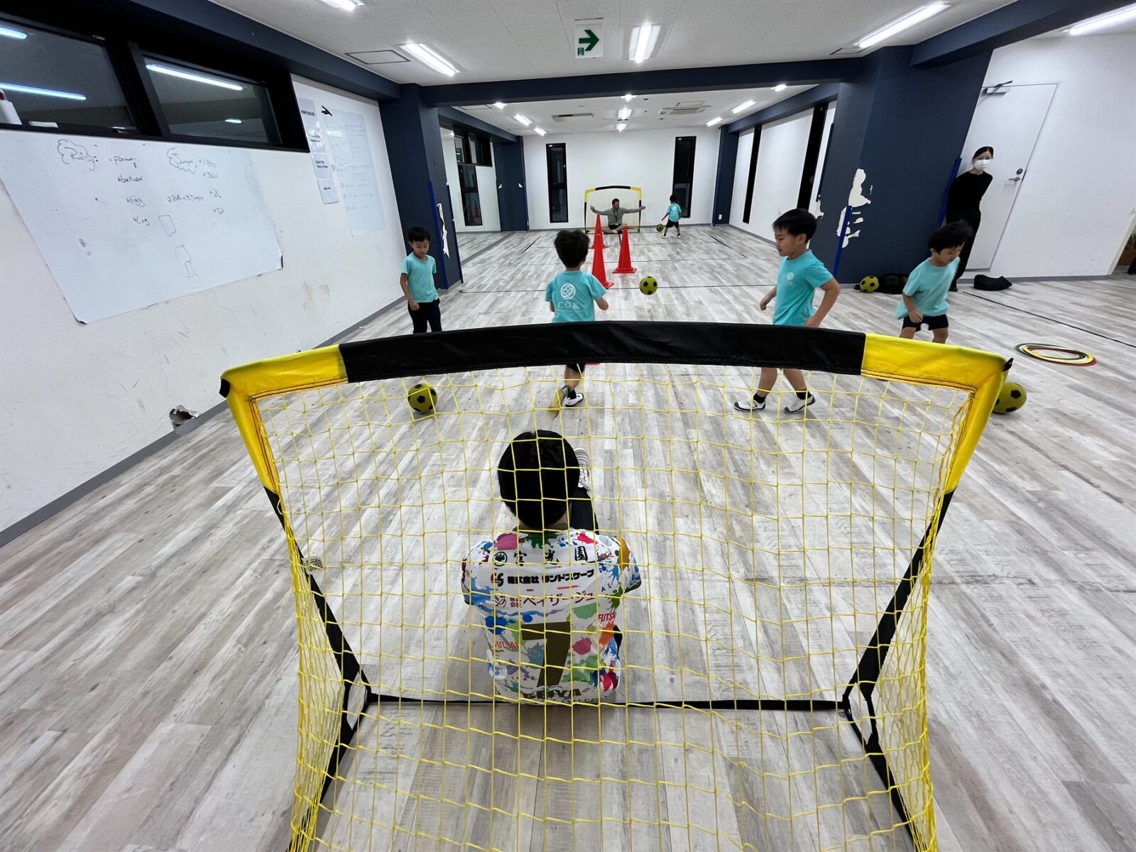 Children playing soccer indoors with a small goal